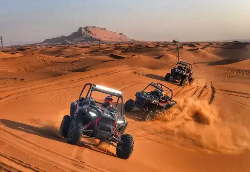 Off-road buggies racing through golden desert dunes under the sun